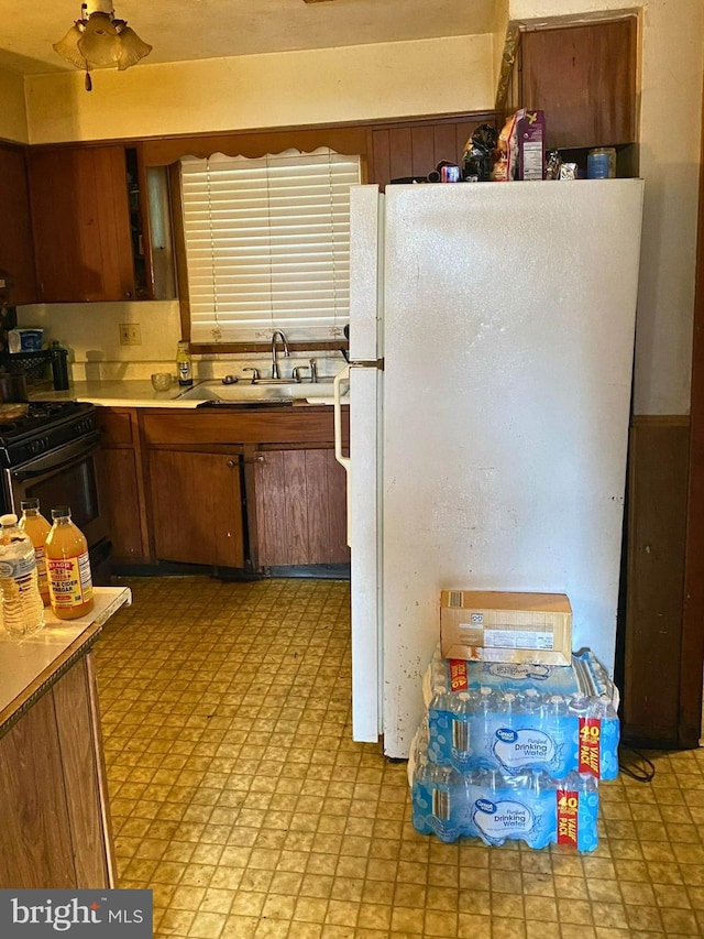 kitchen featuring black gas stove, sink, and white refrigerator