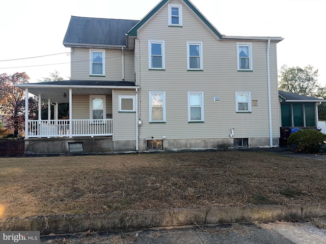 back of property featuring a lawn and covered porch