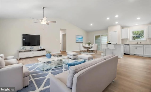 living room featuring sink, vaulted ceiling, and light hardwood / wood-style flooring