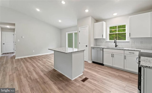 kitchen featuring light stone countertops, white cabinetry, appliances with stainless steel finishes, and a center island