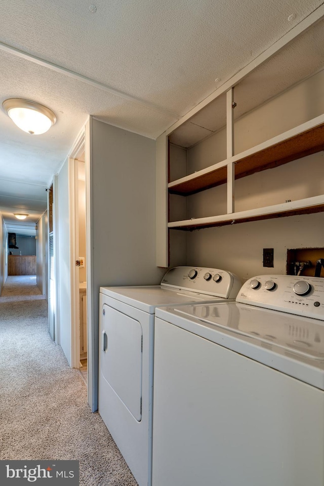 washroom with washer and clothes dryer, a textured ceiling, and light colored carpet