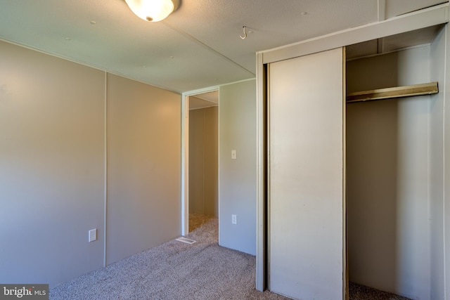 unfurnished bedroom featuring a closet, a textured ceiling, and carpet flooring