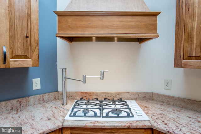 kitchen with white gas stovetop and custom range hood