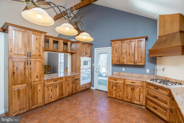 kitchen with beamed ceiling, light stone countertops, custom range hood, white appliances, and pendant lighting