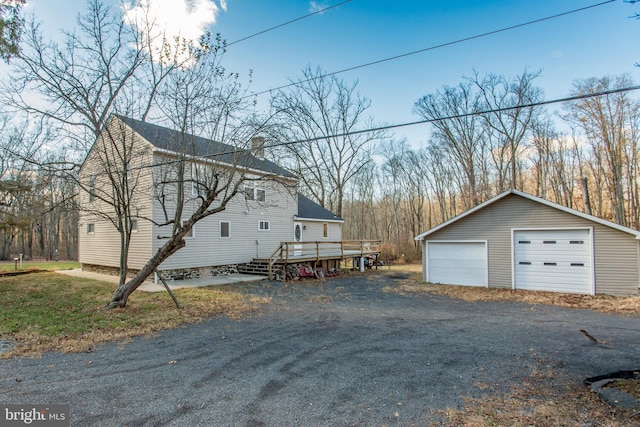 view of side of property featuring a garage, a wooden deck, and an outdoor structure