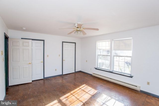 unfurnished bedroom with a baseboard radiator, ceiling fan, dark hardwood / wood-style floors, and two closets