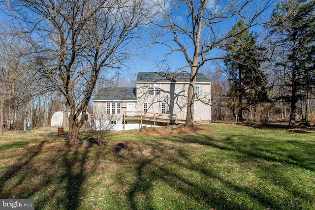 rear view of property featuring a lawn, a storage unit, and a deck