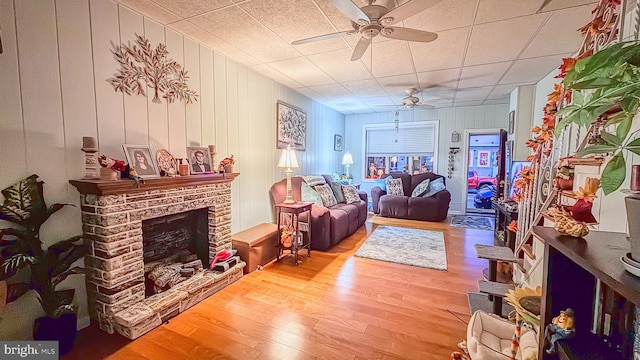 living room featuring light wood-type flooring, a brick fireplace, and ceiling fan