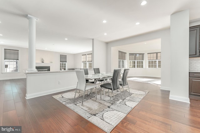 dining room featuring dark wood-type flooring, decorative columns, and a healthy amount of sunlight