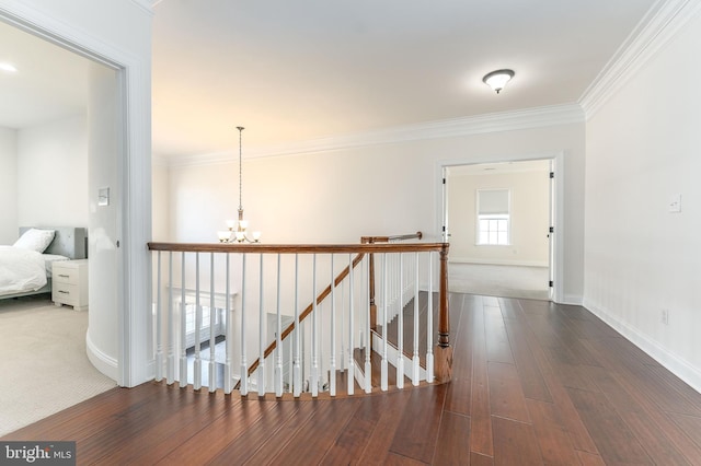 hall with ornamental molding, dark wood-type flooring, and an inviting chandelier