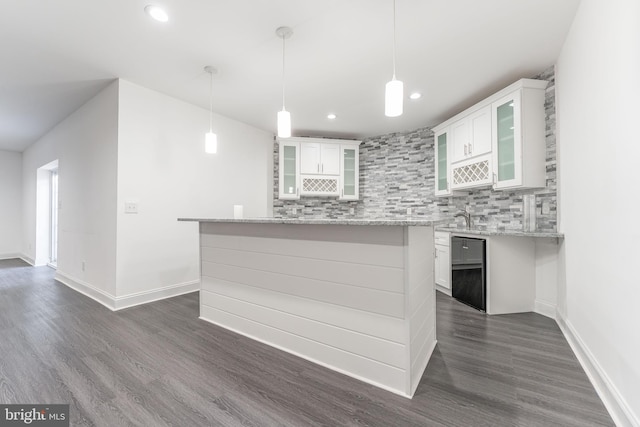 kitchen with light stone countertops, dark hardwood / wood-style flooring, backsplash, decorative light fixtures, and white cabinets