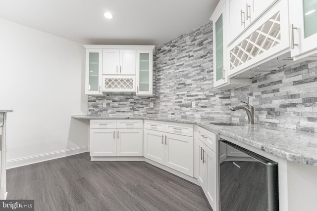 kitchen with white cabinetry, sink, light stone counters, dark hardwood / wood-style floors, and decorative backsplash