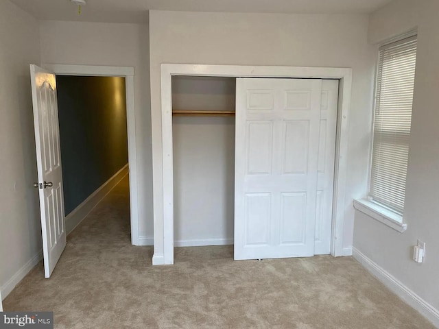 unfurnished bedroom featuring light colored carpet and a closet