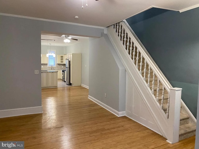 stairway featuring ornamental molding, hardwood / wood-style flooring, and ceiling fan