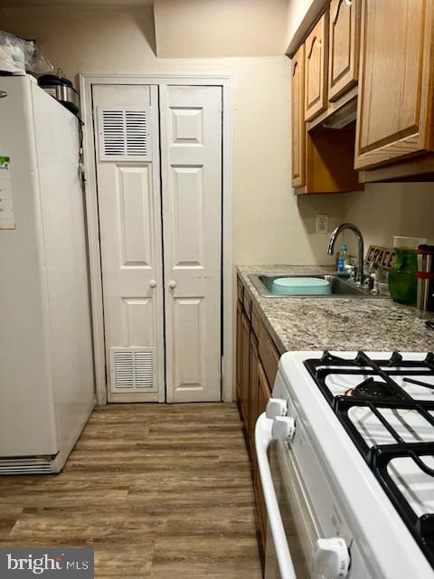 kitchen featuring sink, white appliances, and dark wood-type flooring