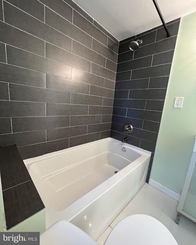 bathroom with tile patterned flooring, tiled shower / bath, and toilet