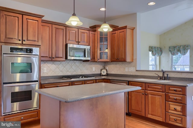 kitchen featuring stainless steel appliances, light wood-type flooring, backsplash, sink, and a center island