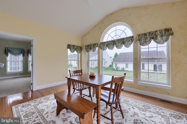 dining area featuring wood-type flooring and vaulted ceiling