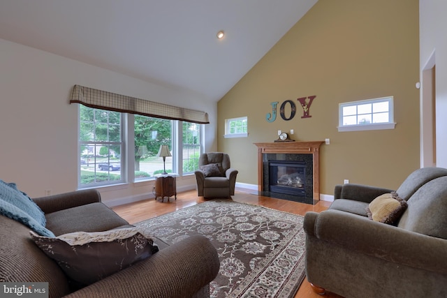 living room with a high end fireplace, plenty of natural light, light hardwood / wood-style flooring, and high vaulted ceiling