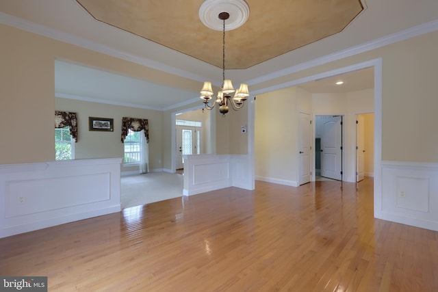 unfurnished room with an inviting chandelier, ornamental molding, and light hardwood / wood-style flooring