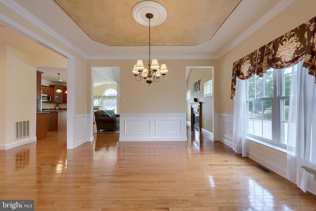 unfurnished dining area with ornamental molding, light wood-type flooring, and a healthy amount of sunlight