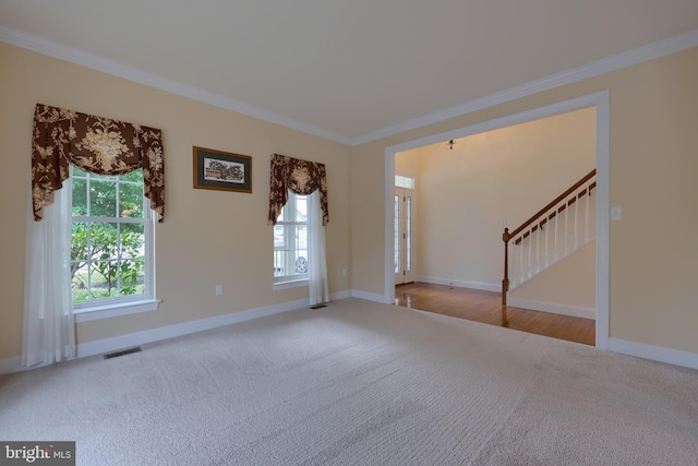 empty room featuring a wealth of natural light, light colored carpet, and crown molding