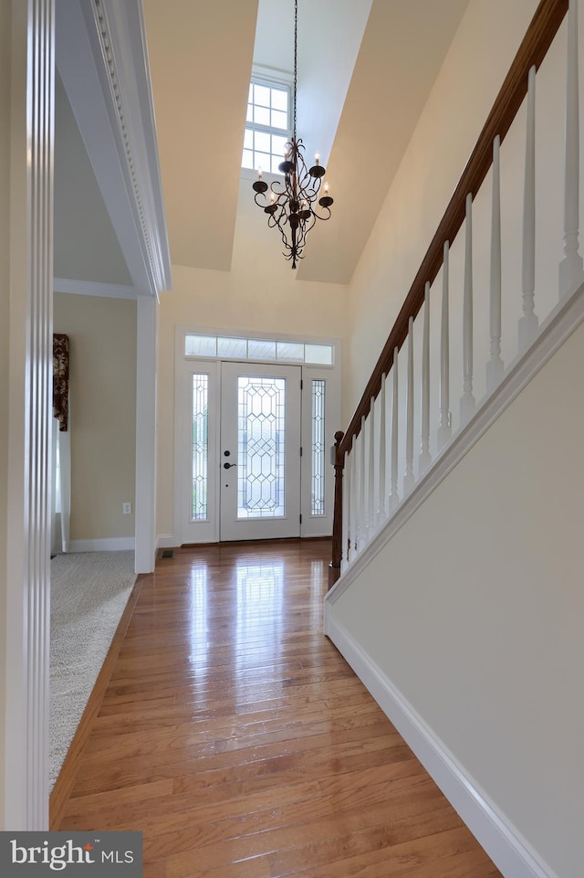 entryway featuring ornamental molding, light hardwood / wood-style floors, a chandelier, and a high ceiling