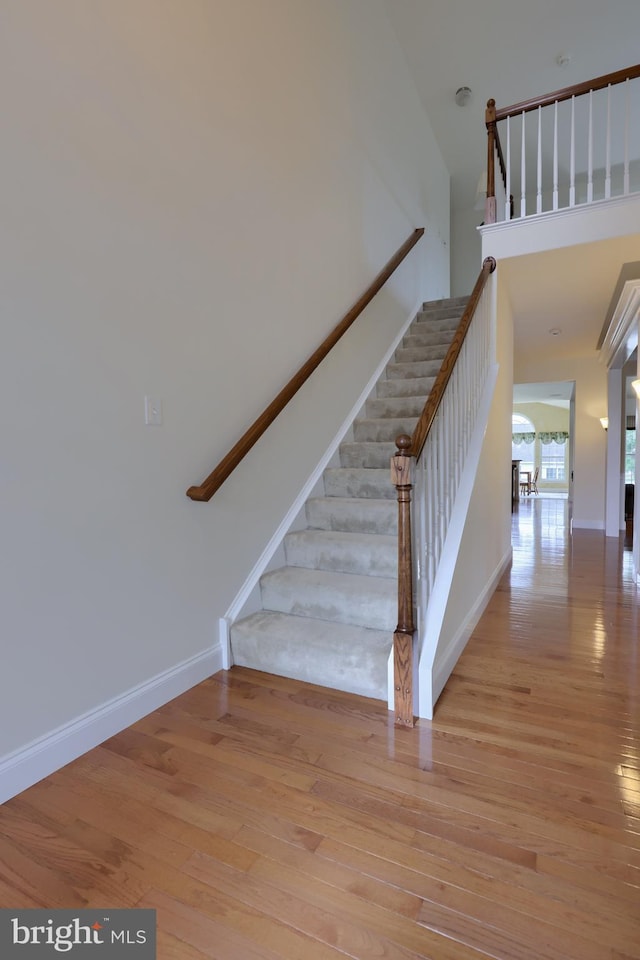 stairway with a towering ceiling and hardwood / wood-style floors