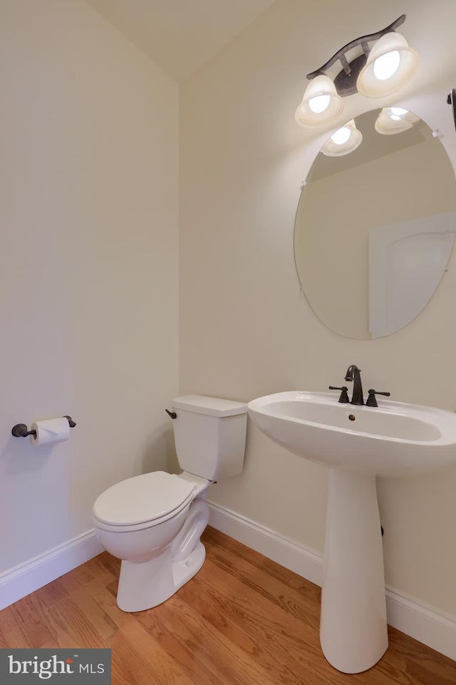 bathroom with toilet, sink, and hardwood / wood-style floors