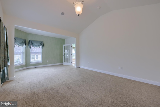 empty room featuring light colored carpet and vaulted ceiling