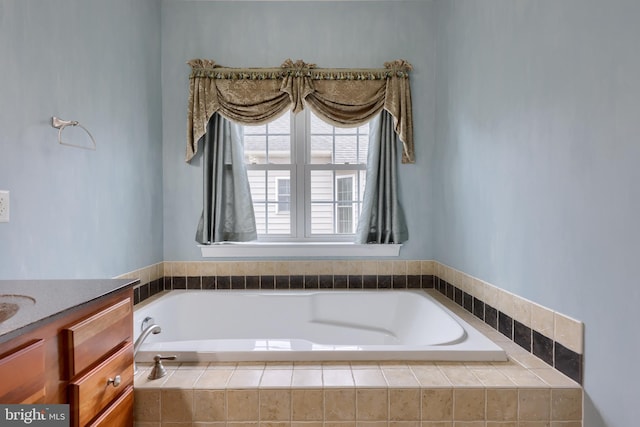 bathroom featuring tiled bath and vanity