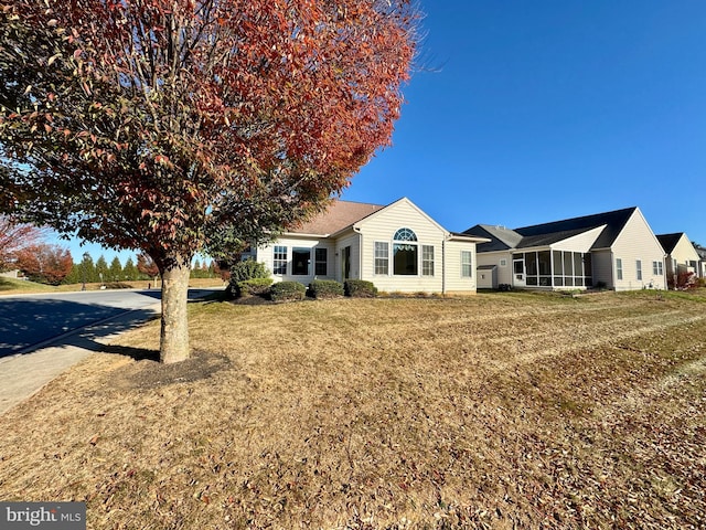 ranch-style house featuring a front lawn and a sunroom