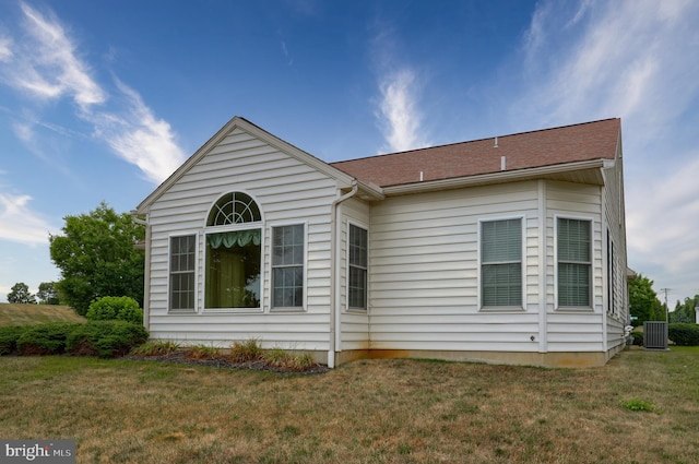 rear view of house with central AC unit and a yard