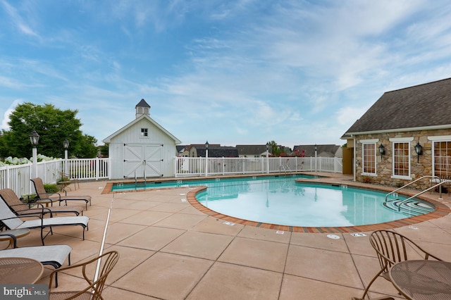 view of swimming pool with an outbuilding and a patio