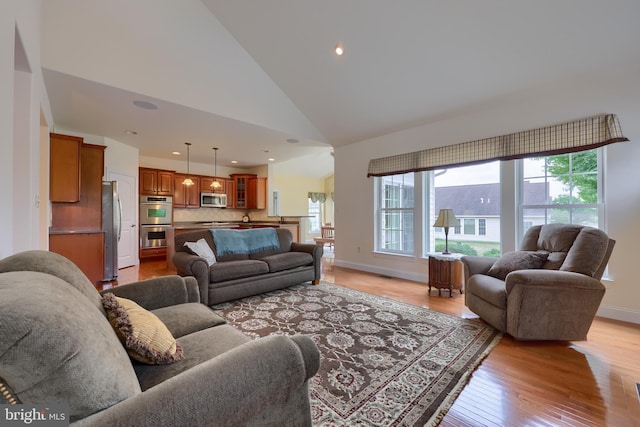 living room with high vaulted ceiling and light wood-type flooring