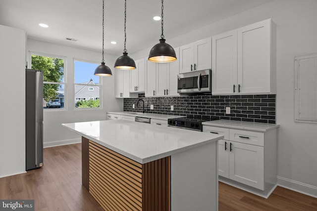 kitchen with white cabinets, dark wood-type flooring, appliances with stainless steel finishes, and a center island