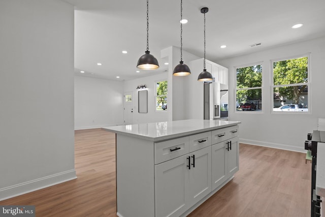 kitchen with a center island, white cabinets, stainless steel refrigerator with ice dispenser, hanging light fixtures, and light wood-type flooring