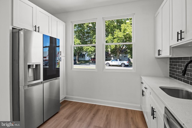 kitchen featuring sink, light stone counters, appliances with stainless steel finishes, tasteful backsplash, and white cabinets