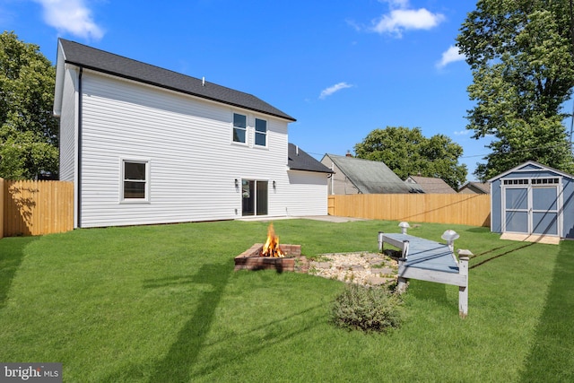 rear view of property with a storage unit, a yard, and a fire pit