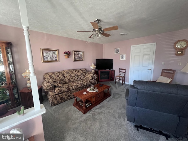 carpeted living room featuring a textured ceiling, decorative columns, and ceiling fan