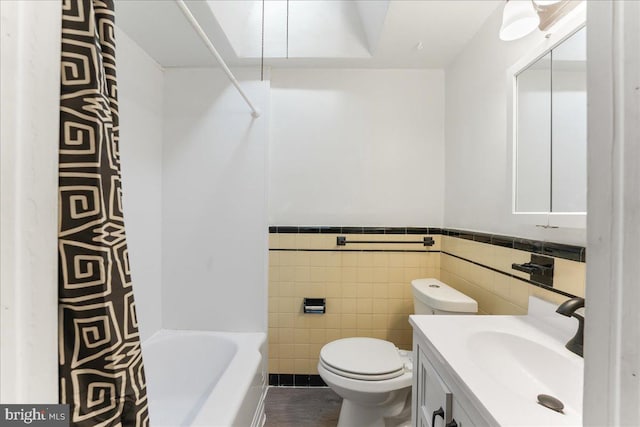 bathroom with vanity, toilet, and tile walls