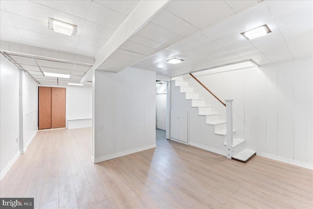 basement featuring light hardwood / wood-style flooring and a paneled ceiling