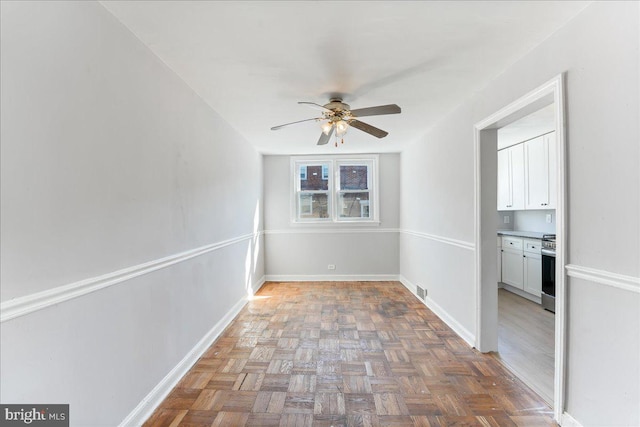 spare room featuring ceiling fan and parquet floors