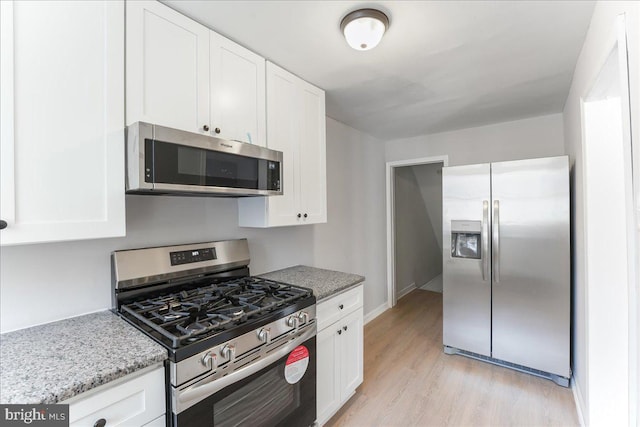 kitchen featuring white cabinets, light stone counters, light wood-type flooring, and appliances with stainless steel finishes