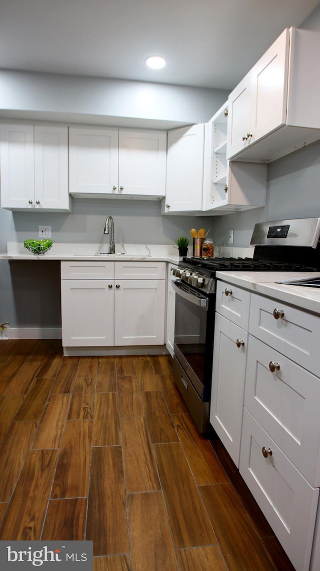 kitchen with white cabinets, stainless steel gas range oven, dark hardwood / wood-style flooring, and sink