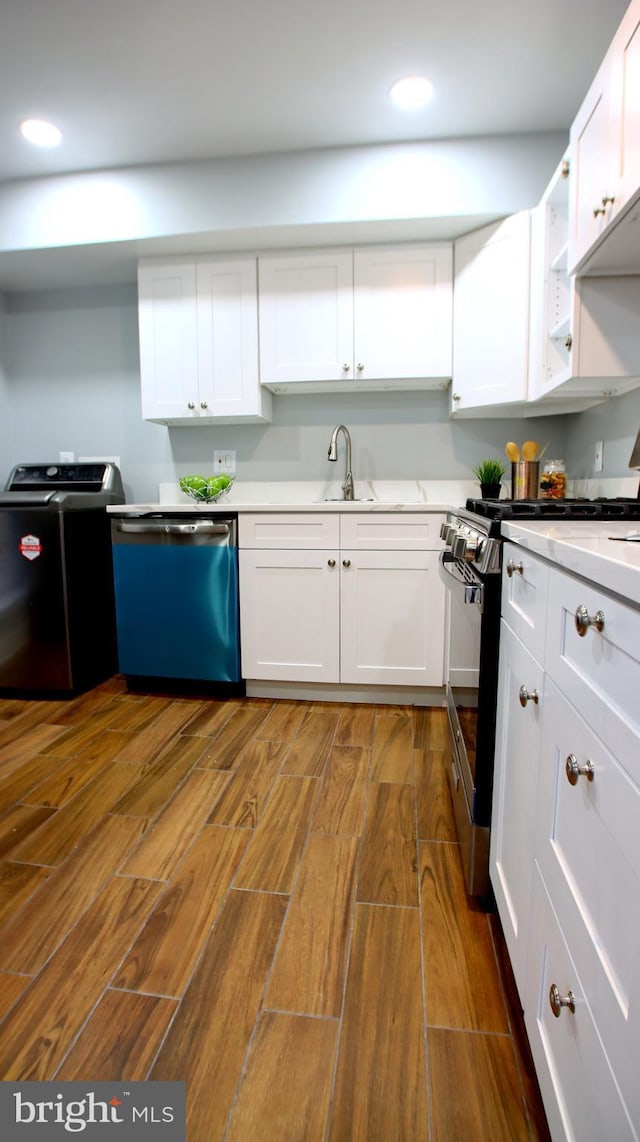 kitchen featuring appliances with stainless steel finishes, white cabinetry, washer and clothes dryer, and dark wood-type flooring