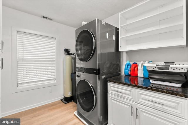 laundry room featuring light wood-type flooring and stacked washer / dryer