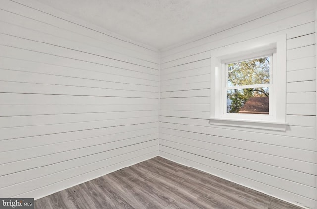 empty room featuring wood walls and hardwood / wood-style flooring