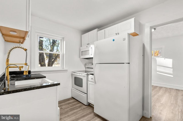 kitchen with sink, white cabinetry, light hardwood / wood-style flooring, white appliances, and dark stone countertops