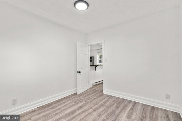 unfurnished room featuring light hardwood / wood-style floors and a baseboard heating unit